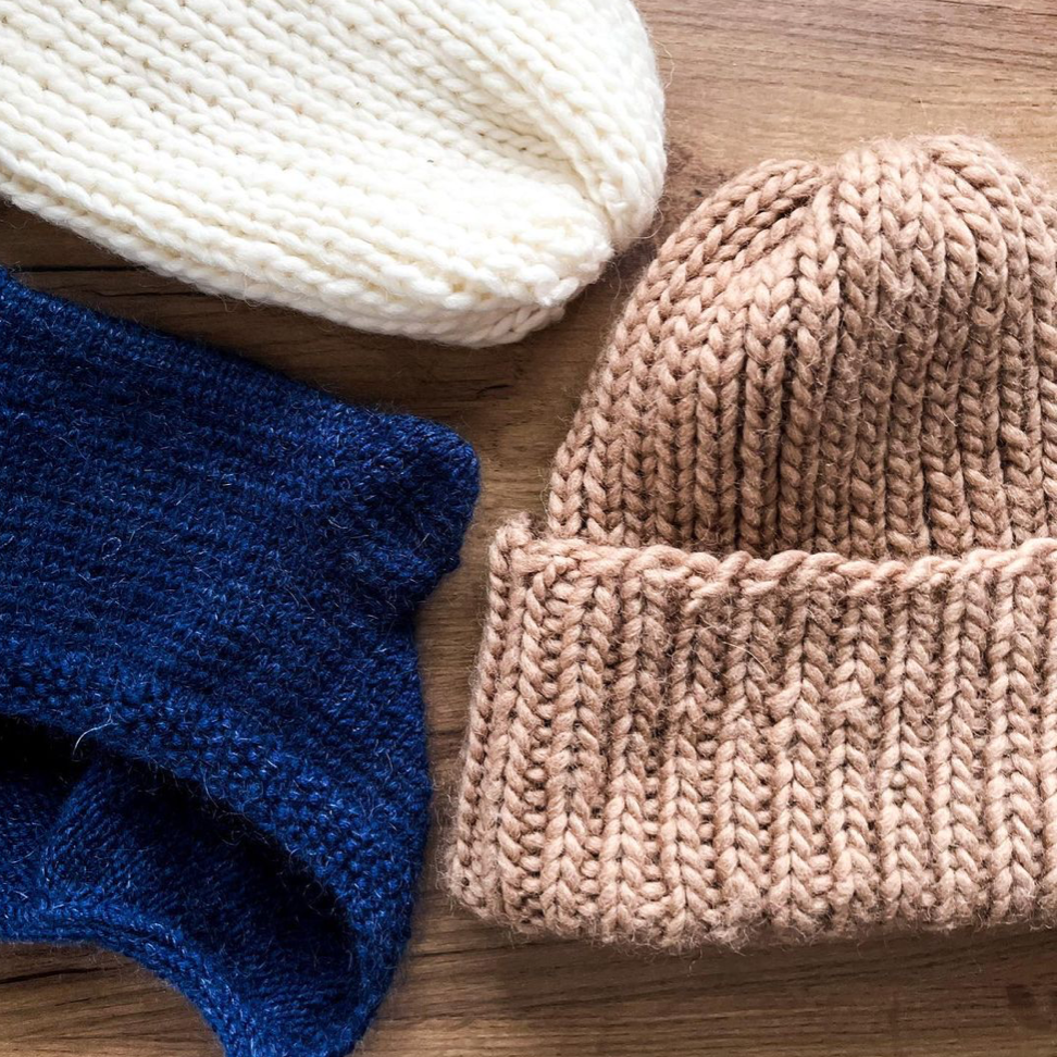 three woolen hats - ecru, peanut butter, navy blue, on the woolen table